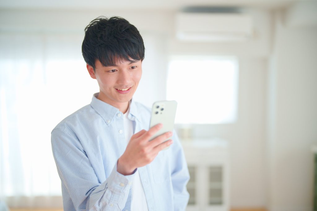 スマホを見てにやにやする男性の写真