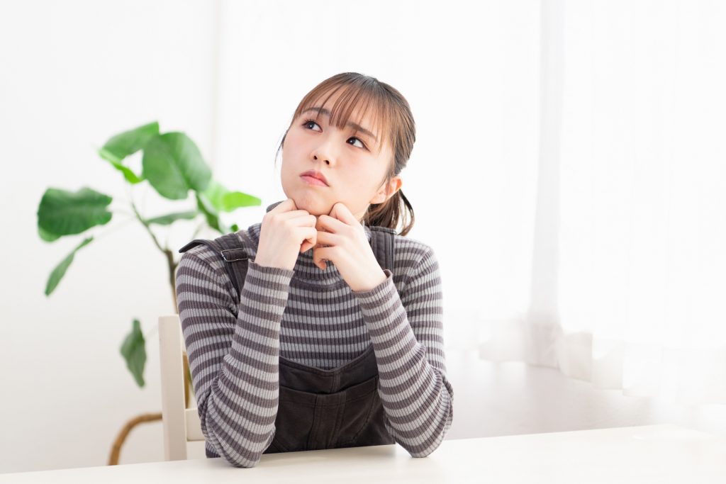 部屋で考え事をしている若い女性の写真